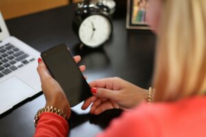 Person at a work desk holding their phone getting ready to use meditation app to take a break from work.