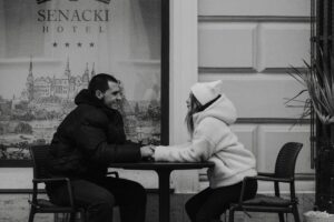 Couples sitting at a table outside holding hands and communicating with one another calmly. 