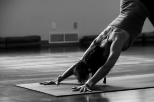 Person on yoga mat doing downward facing dog in a room.