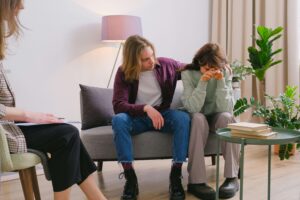 Couple sitting on couch in relationship therapist's office receiving couples counseling by working through difficult emotions