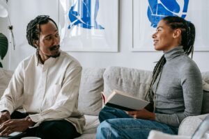 Couple sitting on couch facing each other enjoying their conversation about couples counseling