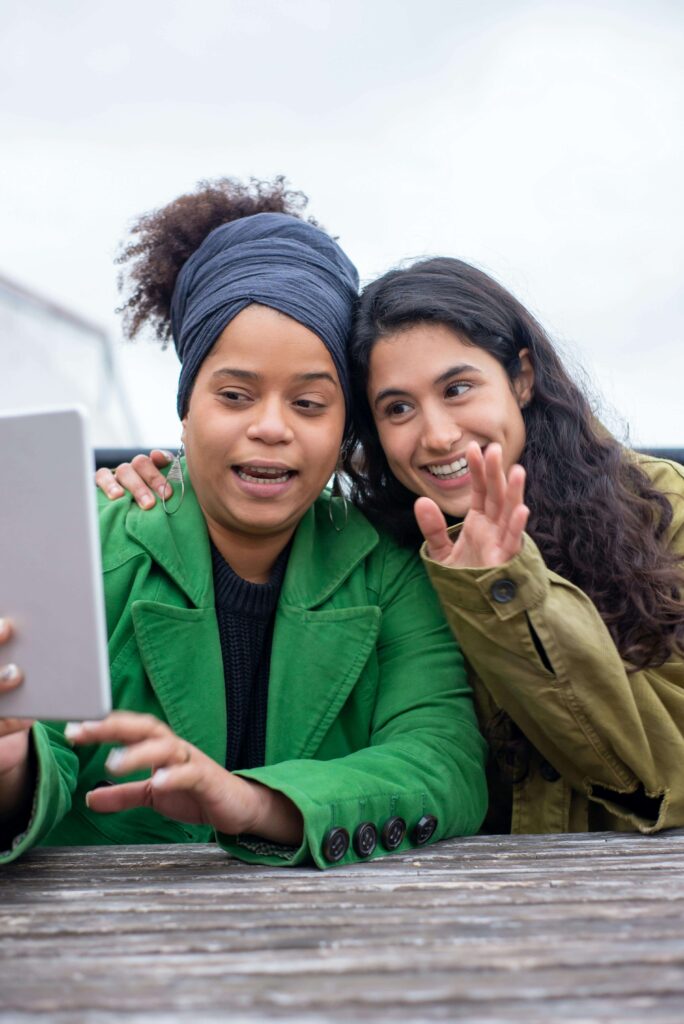 Two people smiling at the laptop as they process the benefits of online therapy in oklahoma.