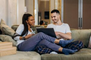 Couple sitting on couch with computer in hand talking about couples counseling