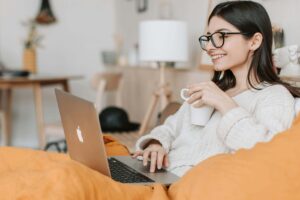 Person seated in a cozy space with blanket and tea preparing for online therapy. 