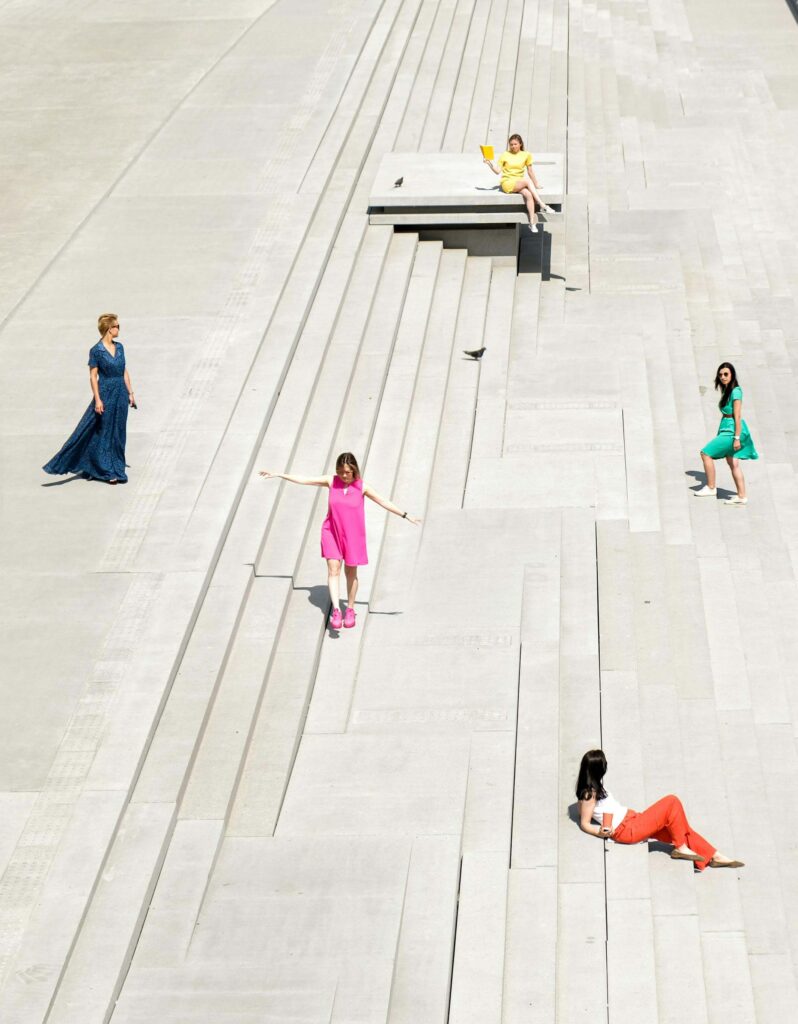 several different levels of stairs where five different people dressed in different colors are each on a different level thus depicting the comparison experienced in life.