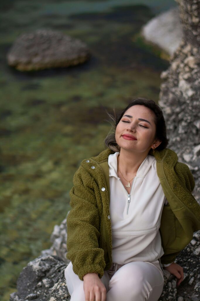 Person smiling up into the sky as they lean back in nature and take a deep breath in.