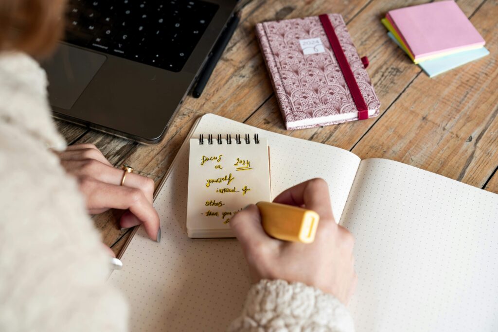 Person reflecting on the last year by writing out things to celebrate and mourn. 