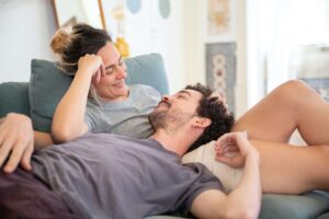 Couple snuggled on couch being present with one another as they were encouraged to do in marriage counseling okc.