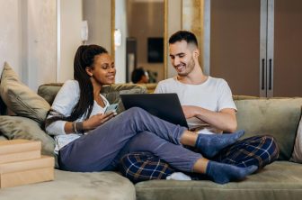 Couple sitting on couch with computer in hand talking about couples counseling