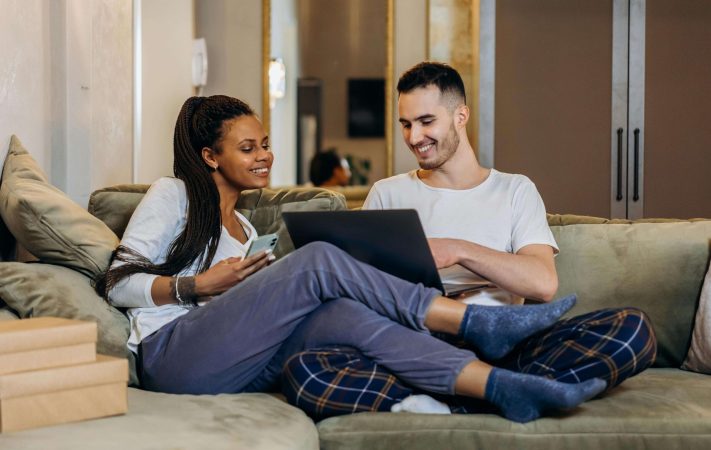 Couple sitting on couch with computer in hand talking about couples counseling