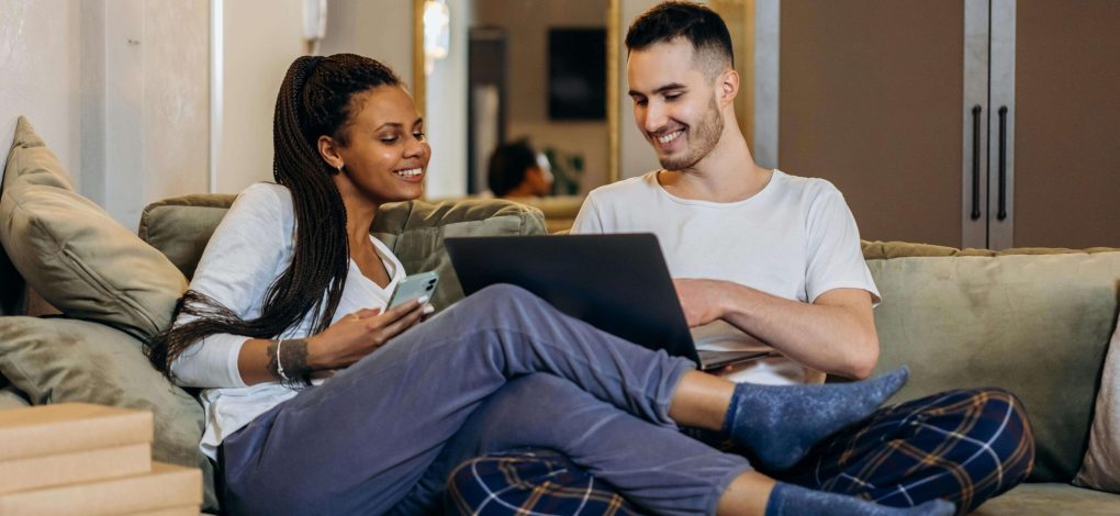 Couple sitting on couch with computer in hand talking about couples counseling