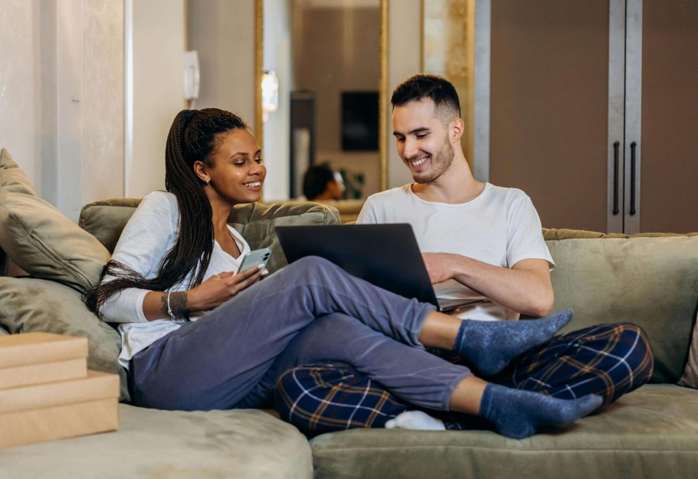 Couple sitting on couch with computer in hand talking about couples counseling