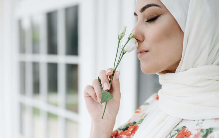 A woman smelling a flower, reflecting on a gentler approach to perfectionism and anxiety therapy